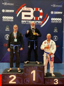 Coach Johnny “Zeus” Tomsett standing on the podium after winning Gold at the 2025 British Open Brazilian Jiu-Jitsu Championships, representing New City Martial Arts Milton Keynes and Southern Tribes BJJ.