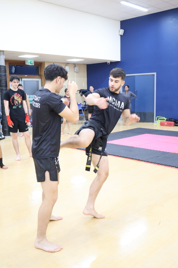 NCMA Kickboxing black belts demonstrating a roundhouse kick during training at Oakgrove School in Milton Keynes.