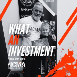 Coach Johnny Tomsett with a young NCMA student holding a martial arts certificate, promoting the blog about martial arts as an investment.