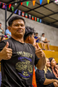 Muay Thai coach and cornerman giving thumbs up at Krabi International Boxing Stadium during live fight event